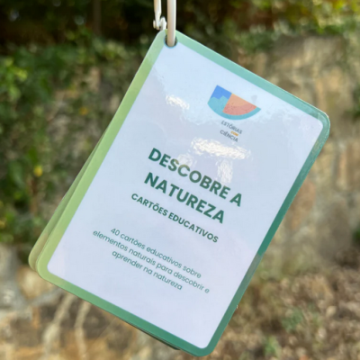 Cartões educativos Descobre a Natureza com 40 cartas sobre elementos naturais pendurados numa argola branca em ambiente exterior