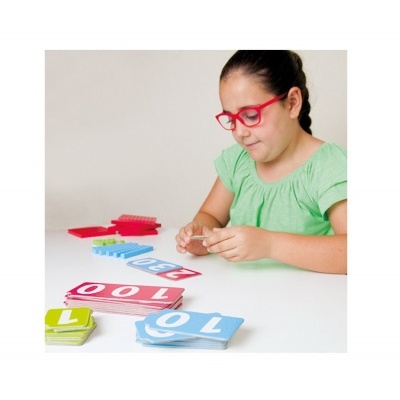 Menina a jogar com cartas e peças coloridas numa mesa branca