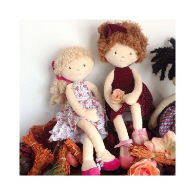 Duas bonecas de pano com vestidos e sapatos cor de rosa sentadas