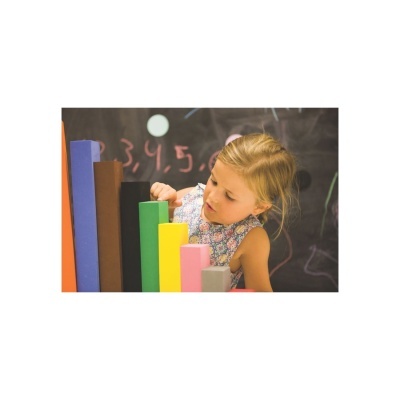 Criança a brincar com blocos de madeira coloridos diante de quadro negro