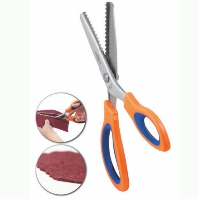 Tesoura com cabo laranja e azul para corte decorativo em tecido vermelho