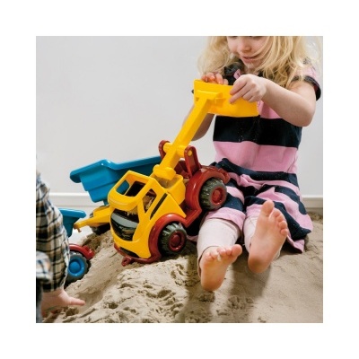 Garota a brincar com escavadora de brinquedo colorida na areia