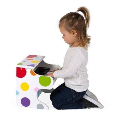 Criança a tocar piano infantil colorido em branco com bolinhas coloridas.