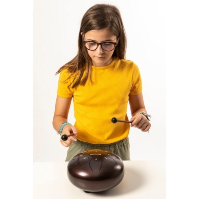 Criança com camisola amarela tocando instrumento de metal redondo castanho