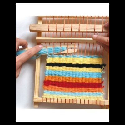 Tear de madeira com fios de lã coloridos sendo tecidos.