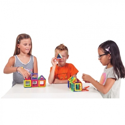Crianças a brincar com peças magnéticas coloridas geométricas numa mesa branca