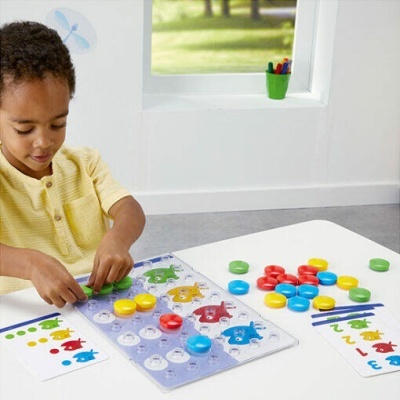 Brinquedo educativo colorido com peças redondas e tabuleiro em mesa branca