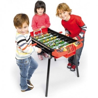 Crianças a jogar futebol de mesa preto e vermelho com campo verde e figuras de jogadores.