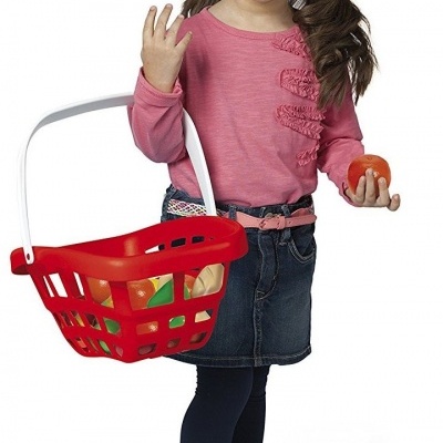 Menina com roupa rosa e azul segurando cesto de brincar vermelho com alimentos de brinquedo