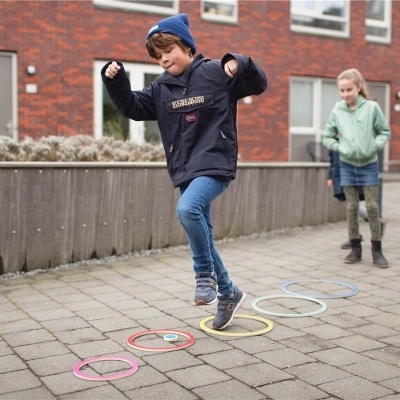 Crianças brincando com círculos coloridos no chão num ambiente urbano