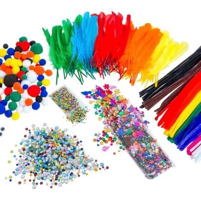 Materiais coloridos para artesanato, incluindo pompons, olhos móveis, penas, canudos felpudos e lantejoulas sobre fundo branco