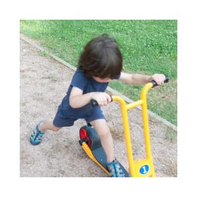 Criança a andar de trotinete amarela num parque com relvado