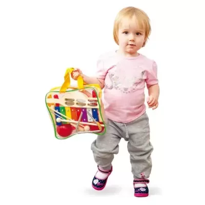 Criança pequena com mala transparente contendo brinquedos musicais coloridos