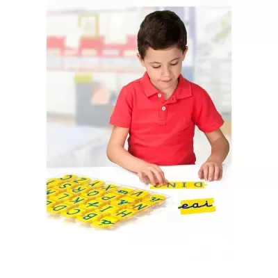 Menino a brincar com peças amarelas de letras azuis para formar palavras.