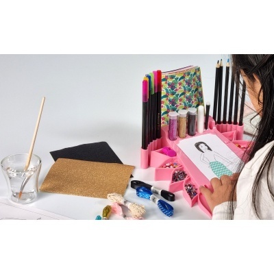 Material de artesanato colorido com suporte rosa e criança a desenhar
