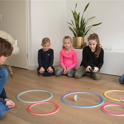 Crianças sentadas no chão a jogar com aros coloridos