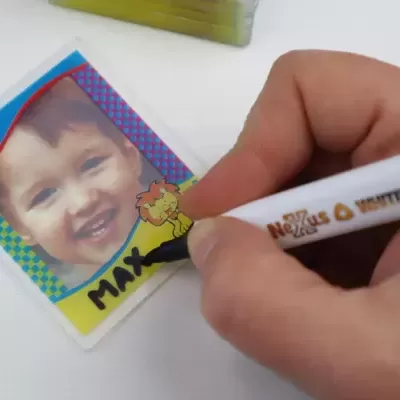 Cartão plástico com foto de criança e escrita à mão feita com marcador branco.