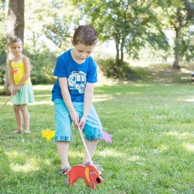 Crianças a brincar com cães de madeira coloridos num parque