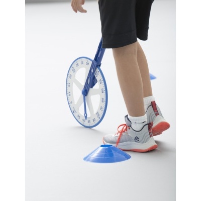 Roda de medição ao lado de cones azuis e pés com ténis brancos e detalhes vermelhos.