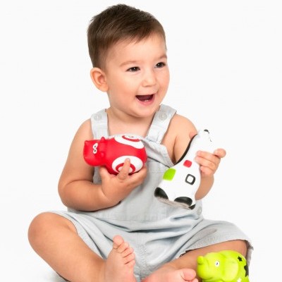 Bebé com brinquedos em forma de vaca, coloridos, sentado