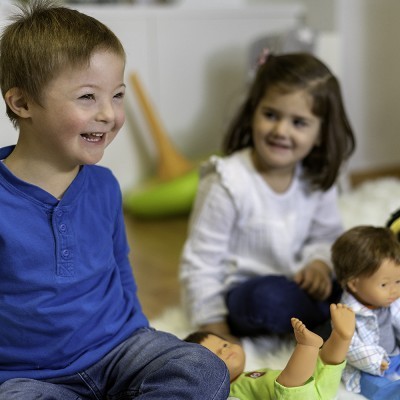 Duas crianças a brincar com bonecos num interior.