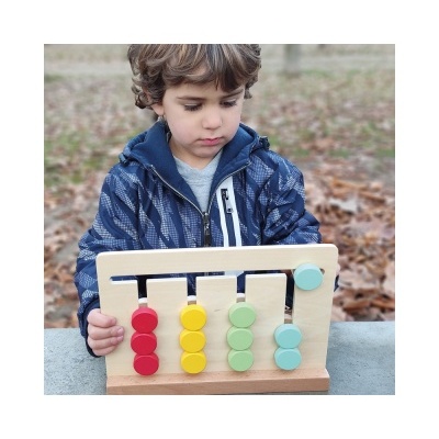 Brinquedo educativo de madeira com colunas coloridas segurado por criança com casaco azul