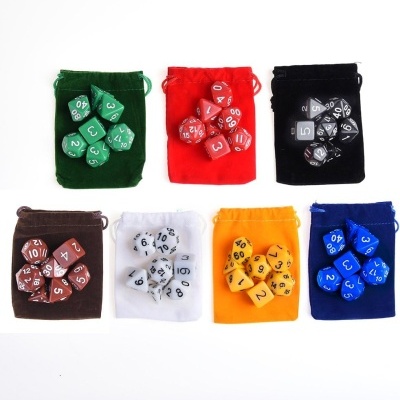 Sete sacos de veludo com dados poliédricos coloridos combinando sobre fundo branco.