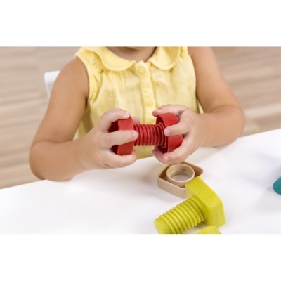 Criança a brincar com porcas e parafusos de plástico coloridos numa mesa branca.