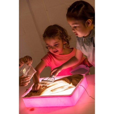 Crianças a brincar com caixa luminosa de areia rosa