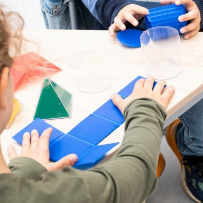 Crianças a montar formas geométricas de plástico colorido numa secretária