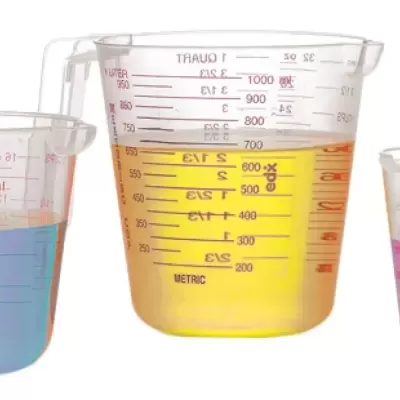 Três copos medidores de plástico com líquidos coloridos