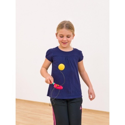 Criança a brincar com raquete e bola presas a elástico