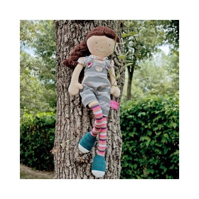 Boneca de pano colorida sentada num tronco de árvore