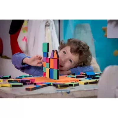 Criança a brincar com blocos coloridos sobre mesa interior