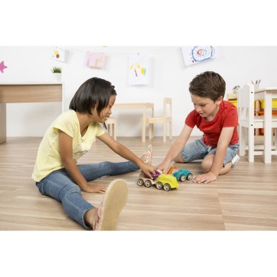 Duas crianças brincando com carrinhos de madeira num chão claro em sala infantil.