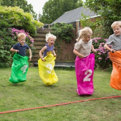 Crianças a saltar em sacos coloridos num jardim