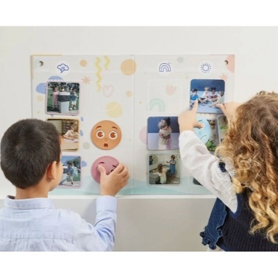 Painel interativo com fotos e ícones de emoções e duas crianças a mexer no painel
