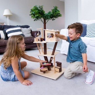 Crianças a brincar com árvore de brinquedo de madeira com móveis pequenos e plantas verdes