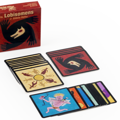 Jogo de cartas Os Lobisomens com caixa e cartas coloridas sobre mesa branca