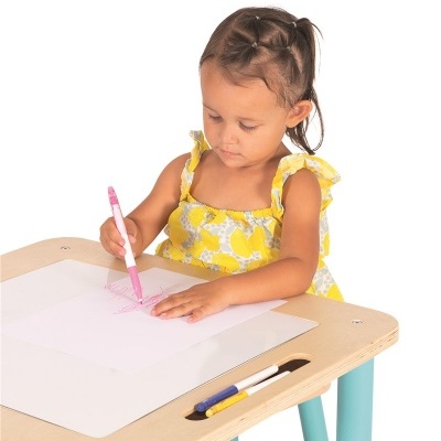 Criança a desenhar numa secretária com canetas