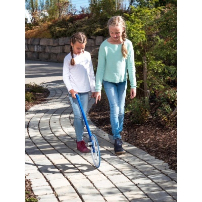 Duas meninas juntas com medidor de distância de rodas azul num caminho de pedra ao ar livre