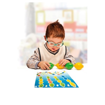 Criança a brincar com brinquedos de limão e tabuleiro colorido em mesa branca