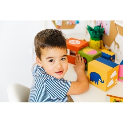 Criança com camisola listrada e blocos de madeira coloridos numa mesa