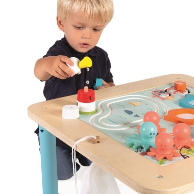 Criança a brincar numa mesa de atividades colorida com peças para encaixar