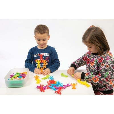 Crianças a brincar com bonecos coloridos de plástico numa mesa branca