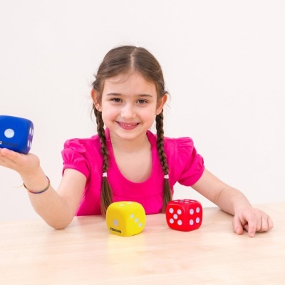 Menina com camisa rosa a brincar com dados coloridos.