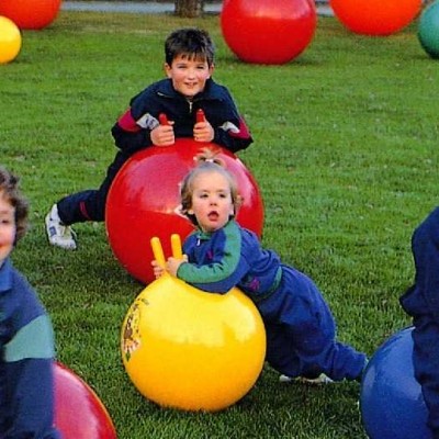Crianças a brincar com bolas de saltar coloridas num relvado