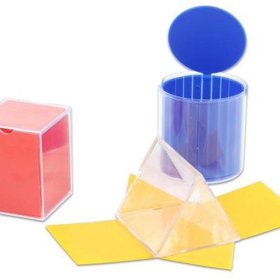 Três caixas plásticas coloridas transparentes: vermelha quadrada, azul redonda e pirâmide transparente com base amarela.