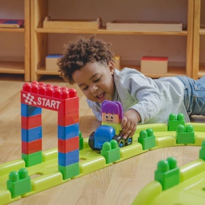 Criança brincando com brinquedo de construção de pista colorida começando no arco START