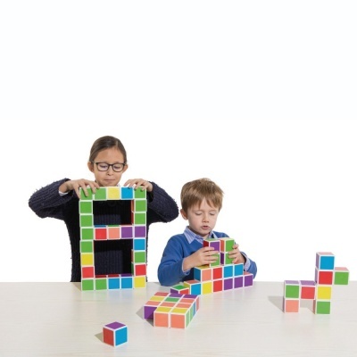 Crianças a brincar com blocos de construção coloridos sobre mesa branca